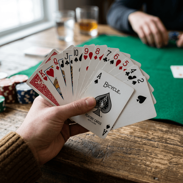 Hand holding a fan of playing cards over a green poker table